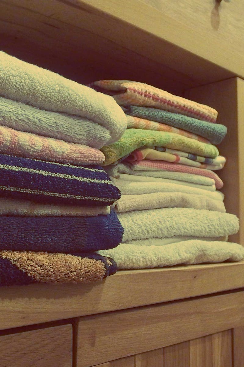 Tidy wooden cabinet with neatly stacked towels and decorative baskets in an indoor setting.