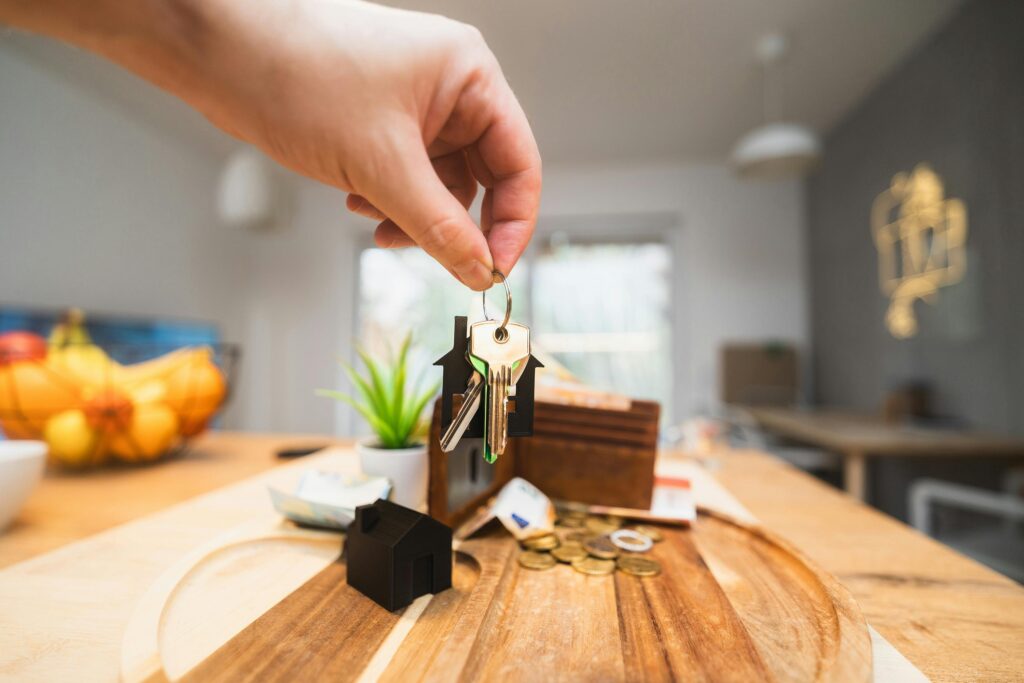 pexels-photo-29726512-29726512 Hand holding keys in a modern living room setting, symbolizing home ownership or real estate investment.